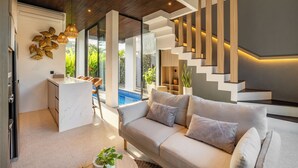 A modern living room with a sofa, a coffee table, and a kitchen area with a marble countertop.