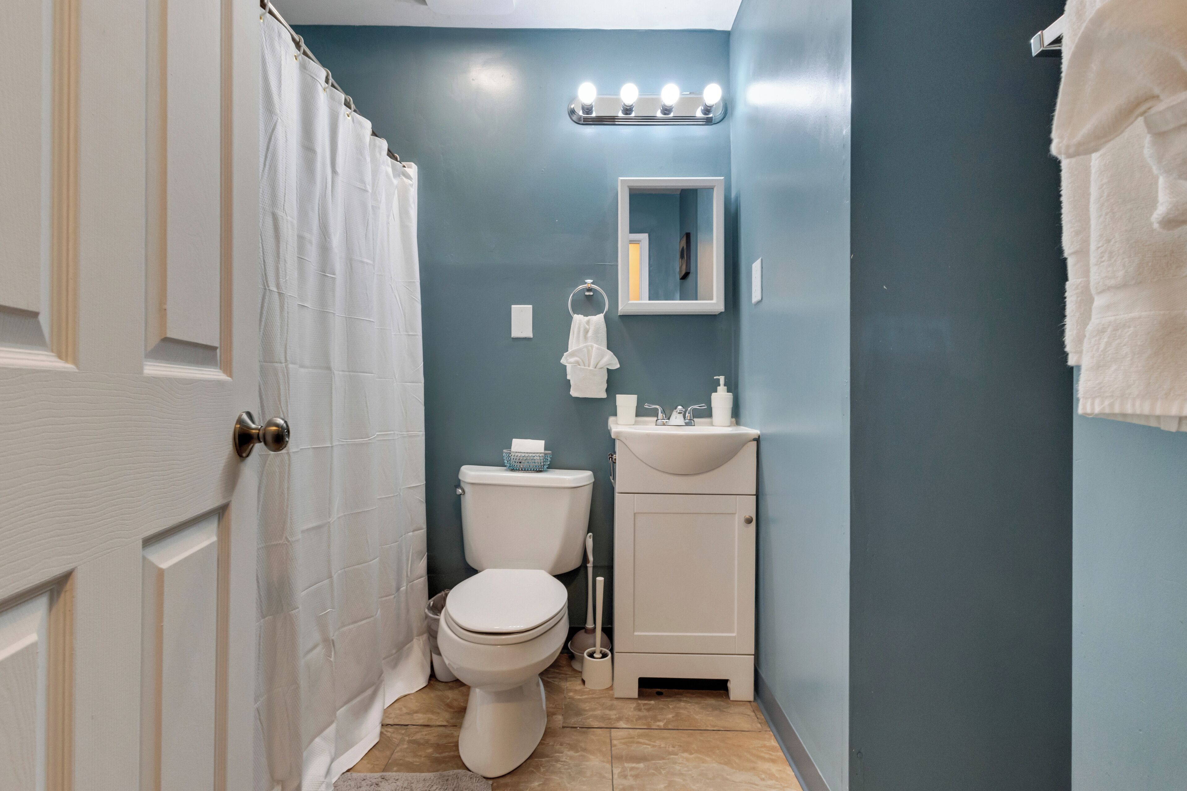 A bathroom with a white toilet, a sink, and a mirror.