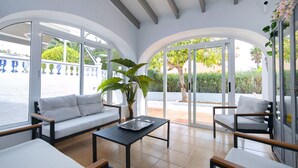 A sunlit patio with white sofas, a black table, and a large plant. - Vacation home Isa by Interhome (Benissa)