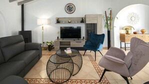 A living room with a fireplace, a TV, a blue chair, a black sofa, and a patterned rug. - Vacation home Isa by Interhome (Benissa)