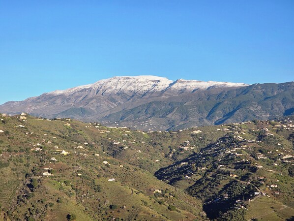A mountainous landscape with scattered buildings, likely a rural or semi-rural area.