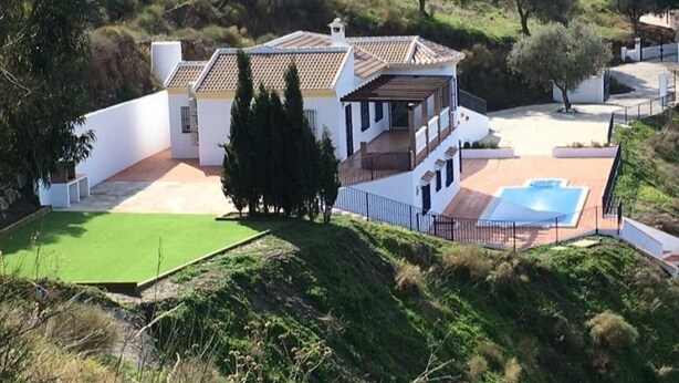 Ett modernt hus med en stor uteplats, en swimmingpool och en frodig trädgård.