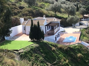 A modern house with a large patio, a swimming pool, and a lush garden.