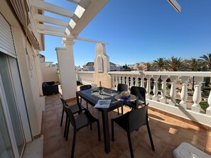 Eine Terrasse mit Tisch für zwei Personen, Stühlen, einer Champagnerflasche und einer Speisekarte.