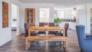 Een moderne eetruimte met een houten tafel en stoelen, een glazen kast en uitzicht op de keuken.
