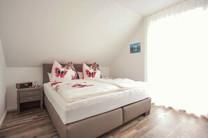 A bedroom with a bed, nightstand, and a window with curtains.