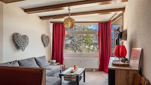 A cozy living room with a sofa, a coffee table, and a red chair.