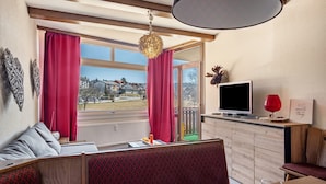 A modern living room with a television, seating area, and a view of the outdoors.