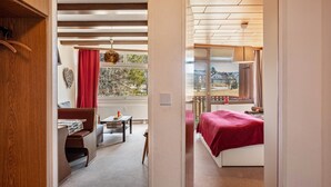 A bedroom with a bed, a desk, and a view of the outside.