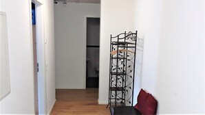 A hallway with a black metal rack, a red cushion, and a white door.