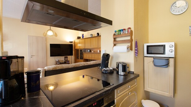Una cucina moderna con piano cottura, forno a microonde e macchina per il caffè.
