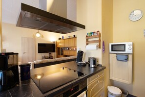 A modern kitchen with a stove, microwave, and coffee maker.