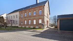 Un edificio a più piani in mattoni con tetto piatto, un garage e un vialetto lastricato.