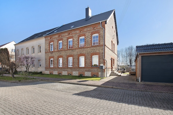 A multi-story brick building with a flat roof, a garage, and a paved driveway.