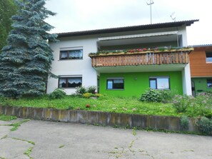 A two-story building with a balcony, a green door, and a satellite dish. - Apartment 'Mit 80qm' with Shared Terrace and Wi-Fi (Ühlingen-Birkendorf)