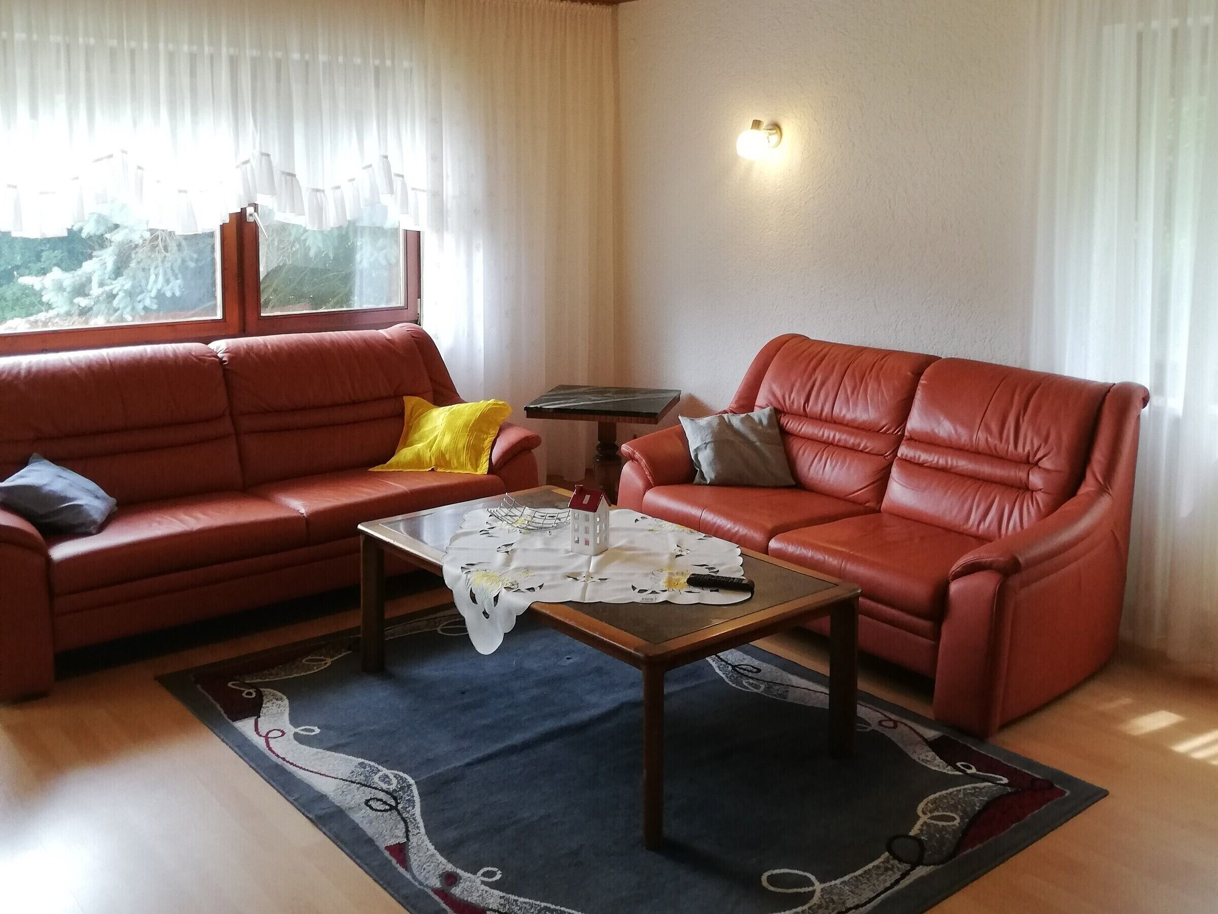 Un salon comprenant un canapé, un fauteuil, une table basse et une vue par la fenêtre.