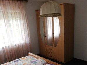 A bedroom with a bed, a wardrobe, and a window with curtains. - Apartment 'Mit 80qm' with Shared Terrace and Wi-Fi (Ühlingen-Birkendorf)