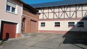 A courtyard with a brick entrance, a wooden door, and a tiled roof. - Holiday Apartment 'Auf Dem Land' with Shared Terrace, Shared Garden and Wi-Fi (Badenhard)