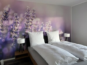 Un dormitorio con una cama, dos mesitas de noche y un mural en la pared.