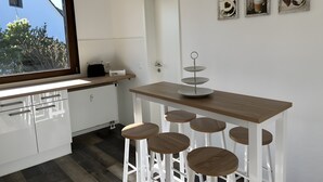 A modern kitchen with white cabinets, a wooden countertop, and a window with a view of trees. - Haus Blumenglück "Lavender and Dandelion" – Two Apartments for up to 11 Guests (Herscheid)