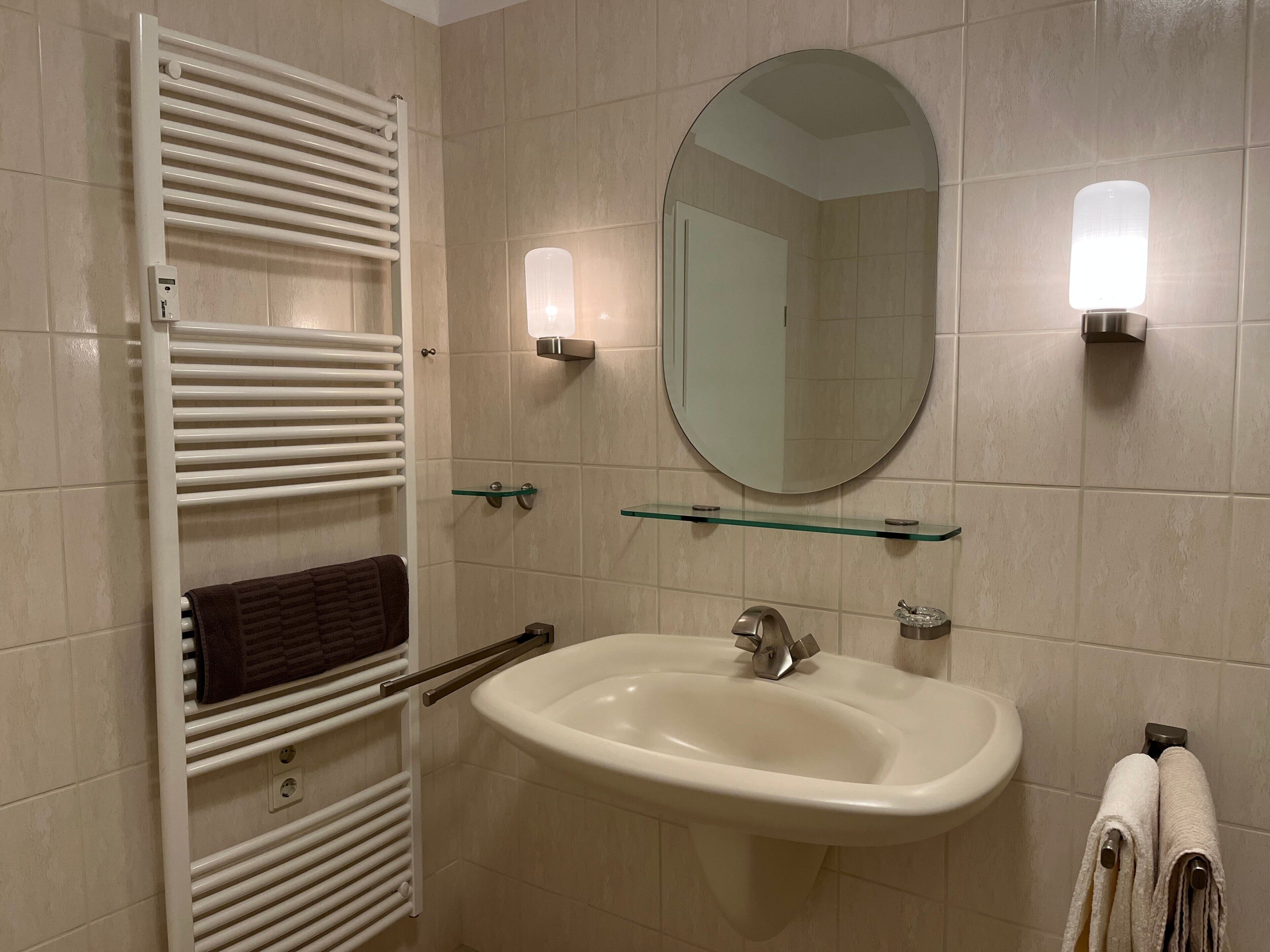 A bathroom with a white sink, a mirror, and a towel rack.