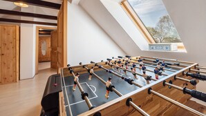 A room with a foosball table, wooden flooring, a skylight, and a view of trees. - Holiday Home 'Mittelhuus' with Private Terrace, Private Garden and Wi-Fi (Wangerland)