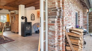 A rustic interior with a fireplace, wooden furniture, and a brick wall. - Holiday Home 'Mittelhuus' with Private Terrace, Private Garden and Wi-Fi (Wangerland)