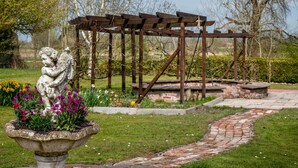 A garden with a pergola, a stone statue, and a brick pathway. - Holiday Home 'Mittelhuus' with Private Terrace, Private Garden and Wi-Fi (Wangerland)