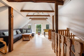 An attic room with a wooden ceiling, a sofa, a coffee table, and a foosball table. - Apartment 'Süderhuus' with Private Terrace, Private Garden and Wi-Fi (Wangerland)