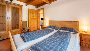 Un dormitorio con dos camas, un armario de madera y una mesita de noche con lámpara.