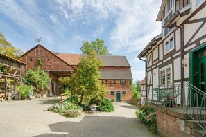 A courtyard with a traditional building, a wooden structure, and a green door.