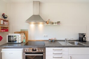 Une cuisine moderne équipée d’un four encastré, d’un four à micro-ondes et d’une hotte en acier inoxydable.