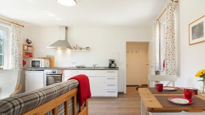 A compact kitchen with modern appliances, a dining area with a wooden table, and a cozy seating area with a bench. - Apartment 'Die Fuchsmühle' with Shared Terrace, Shared Garden and Wi-Fi (Liebenau)