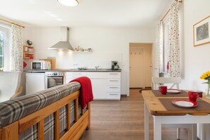 A compact kitchen with modern appliances, a dining area with a wooden table, and a cozy seating area with a bench. - Apartment 'Die Fuchsmühle' with Shared Terrace, Shared Garden and Wi-Fi (Liebenau)
