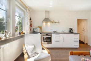 A modern kitchen with white cabinetry, a built-in oven, and a microwave.