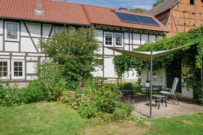 Ein traditionelles Fachwerkhäuschen mit Garten, Bank und Tisch.
