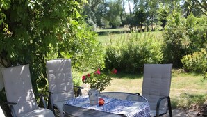An outdoor patio with a round table, two chairs, a potted plant, and a decorative item. - Apartment 'Die Fuchsmühle' with Shared Terrace, Shared Garden and Wi-Fi (Liebenau)