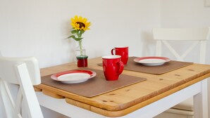 A dining table with a vase of sunflowers, two red mugs, and a white chair. - Apartment 'Die Fuchsmühle' with Shared Terrace, Shared Garden and Wi-Fi (Liebenau)