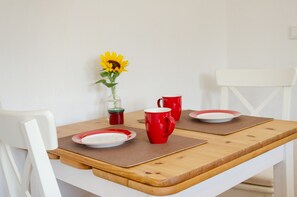A dining table with a vase of sunflowers, two red mugs, and a white chair. - Apartment 'Die Fuchsmühle' with Shared Terrace, Shared Garden and Wi-Fi (Liebenau)