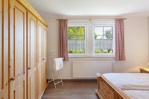 A bedroom with a wooden wardrobe, a radiator, a window with curtains, and a bed. - Apartment 'Die Fuchsmühle' with Shared Terrace, Shared Garden and Wi-Fi (Liebenau)