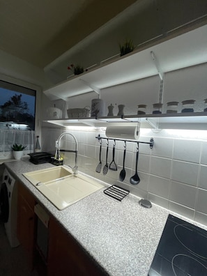 A kitchen with two sinks, a countertop, hanging utensils, and a window with a view. - Apartment 'Ruhige Zeithain' with Private Garden, Wi-Fi and Air Conditioning (Zeithain)