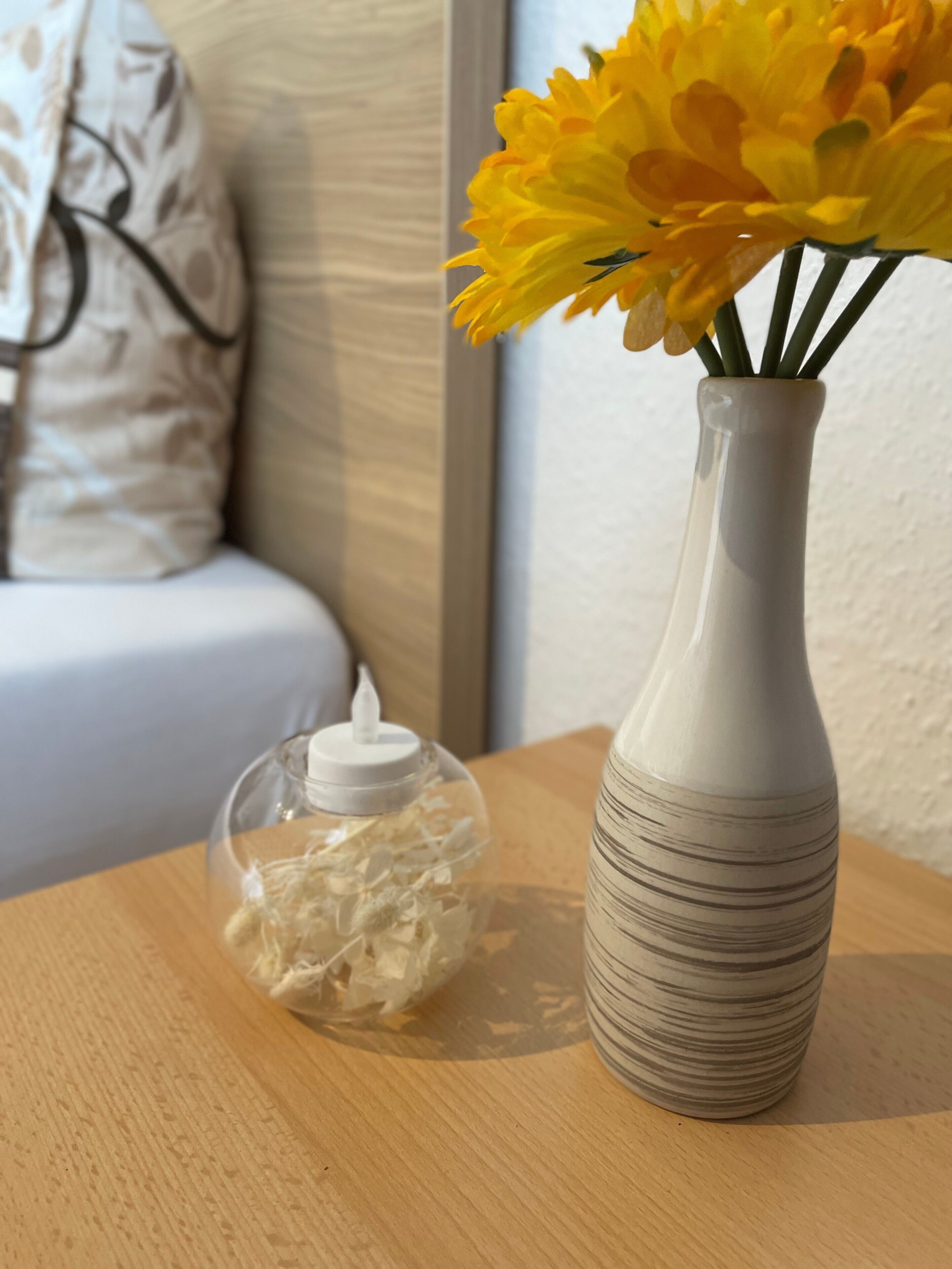 Um vaso de vidro transparente com flores amarelas sobre uma mesa de madeira.