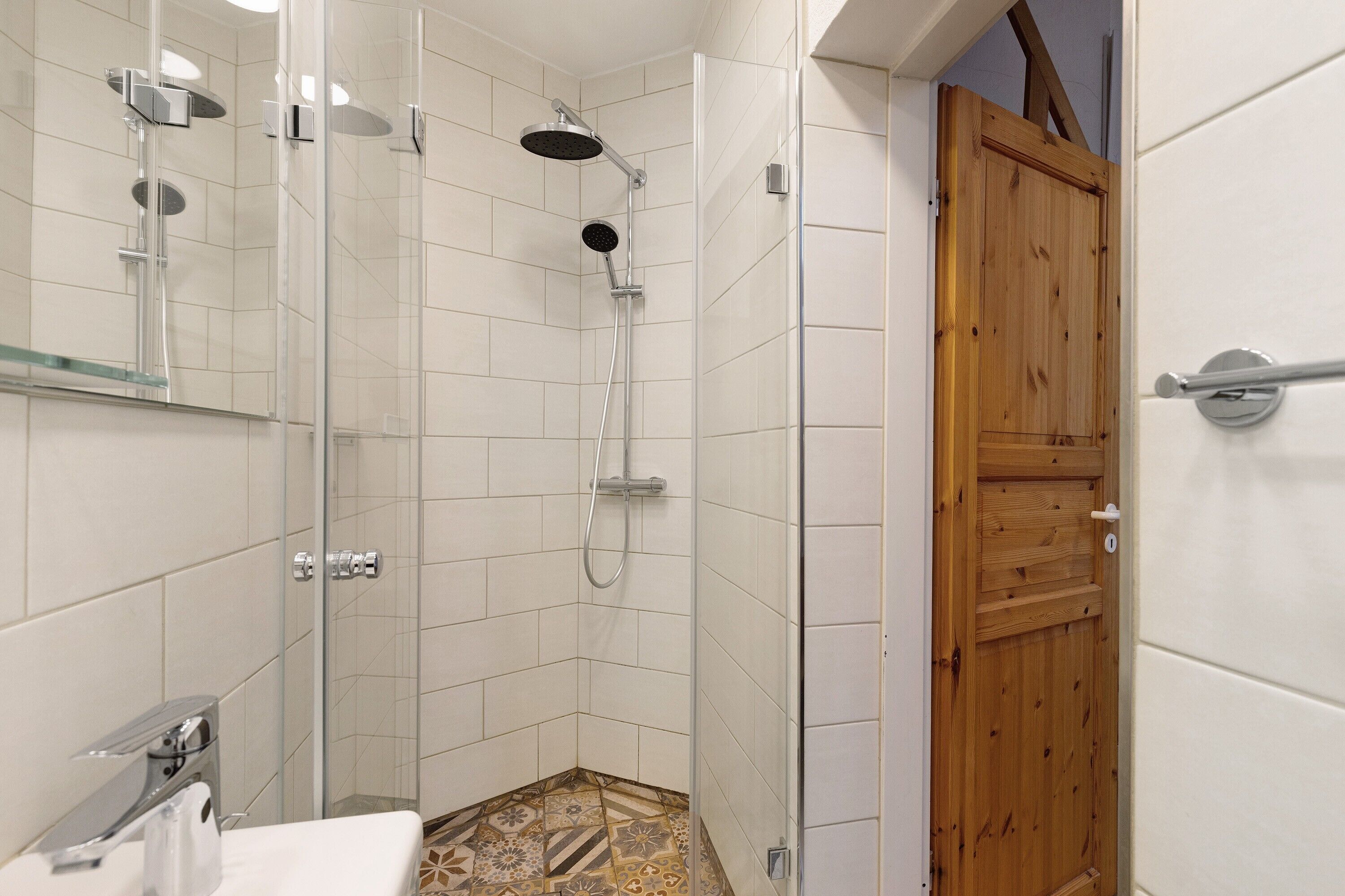 A bathroom with a shower, a sink, and a wooden door.