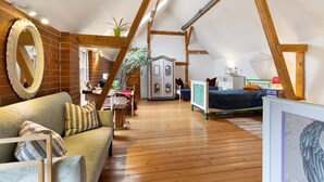 A loft bedroom with a wooden floor, a bed, a dresser, a mirror, and a plant. - Finca 'Gottsdorf' with Private Terrace and Shared Garden (Nuthe-Urstromtal)
