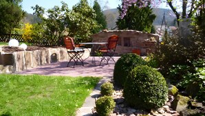 A patio with outdoor furniture, a stone wall, and a garden path. - Apartment 'Bergfrieden' with Private Terrace, Shared Garden and Wi-Fi (Bad Herrenalb)