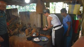 Una cocina rústica con estufa tradicional, utensilios de cocina y una persona preparando comida.