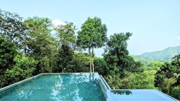 Una piscina infinita con vistas claras a la vegetación y colinas circundantes.