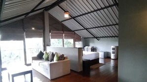 Una habitación amplia con techo alto, una cama, un sofá y una pequeña mesa.