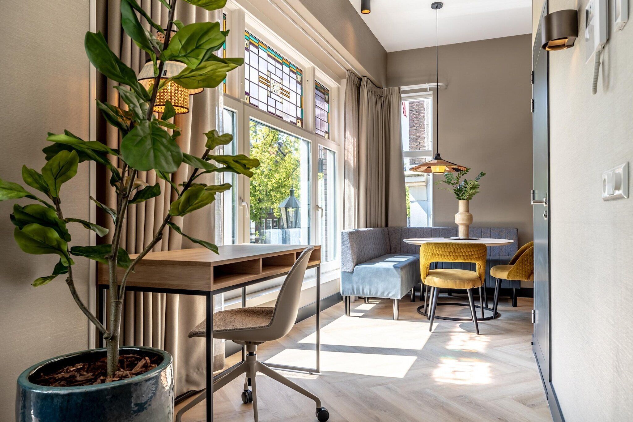 Un espace de bureau moderne comprenant un bureau, un fauteuil de bureau et un coin salon avec un canapé et des fauteuils.