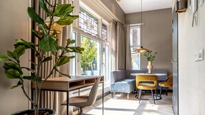 A modern office space with a desk, office chair, and a seating area with a sofa and chairs. - Beautiful apartment, view of Delft canal. (Delft)